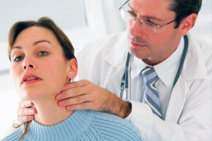 Доктор осматривает щитовидную железу пациента на наличие АИТ